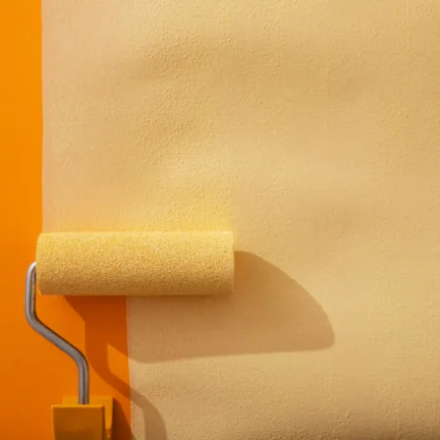 Rodillo pintando una pared de color amarillo