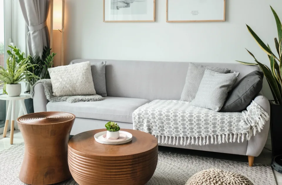 Salón con sofá gris, mesas de madera y suelo de tarima
