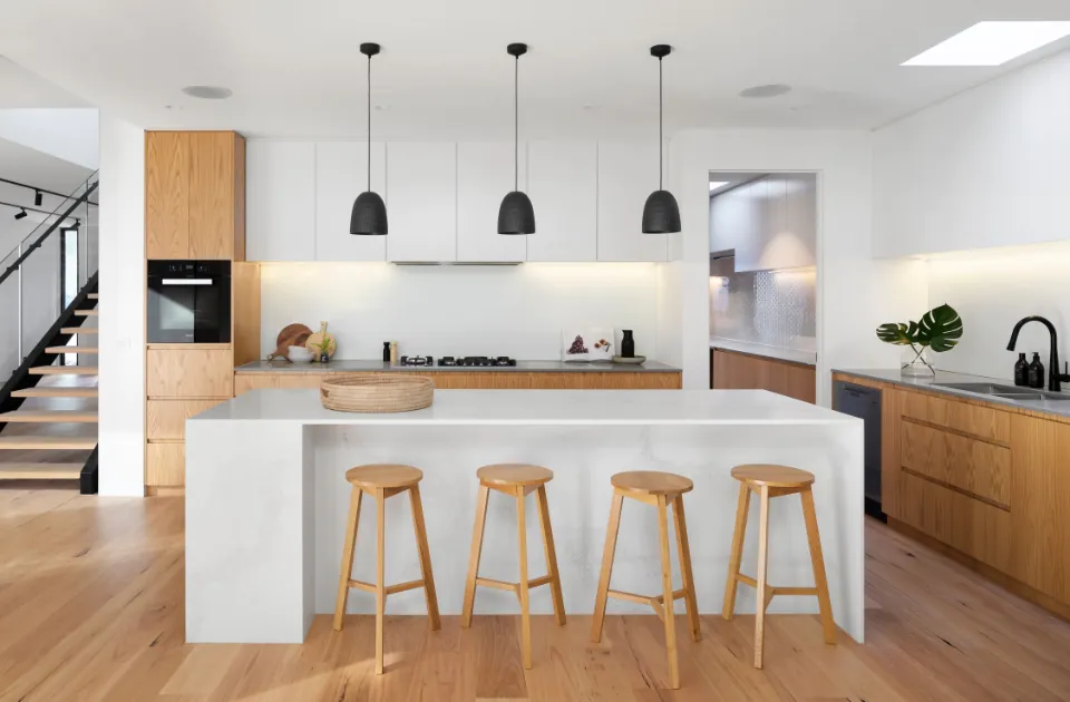 Cocina abierta con isla, lámparas colgantes y suelo de madera